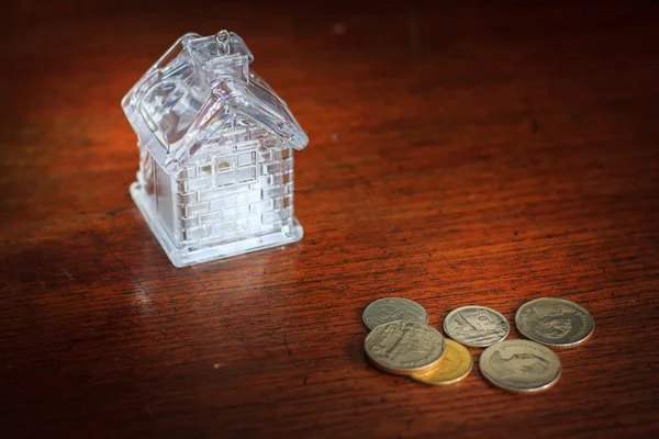 Pequeña casa y monedas en textura de fondo de madera — Foto de Stock