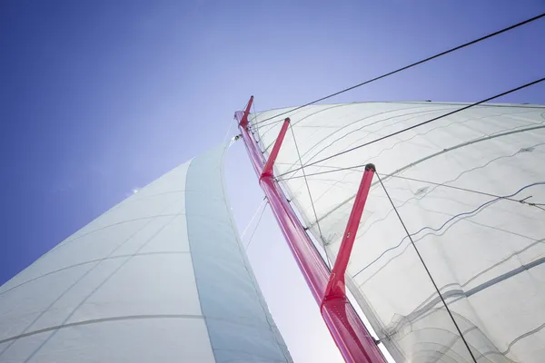 Jacht w akcji, wielki biały żagiel podniesiony nad niebieski niebo jasne — Zdjęcie stockowe