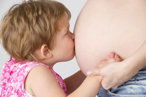 Kind zoenen buik van zwangere vrouw — Stockfoto