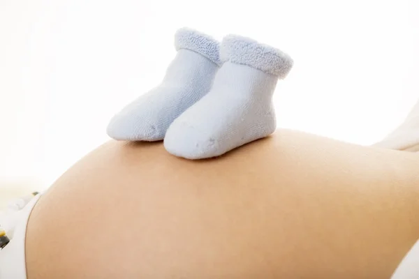 Sapatos de bebê na barriga — Fotografia de Stock