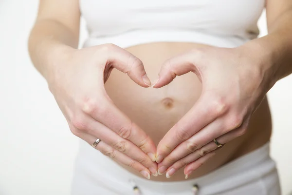 Mujer embarazada haciendo forma de corazón con las manos — Foto de Stock