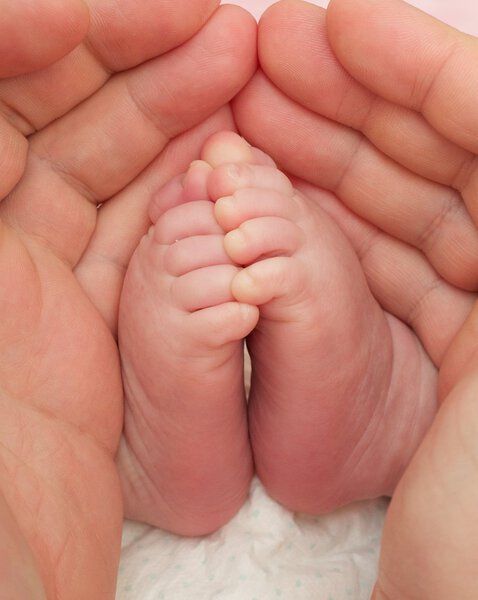 Мать держит ножки новорожденных
