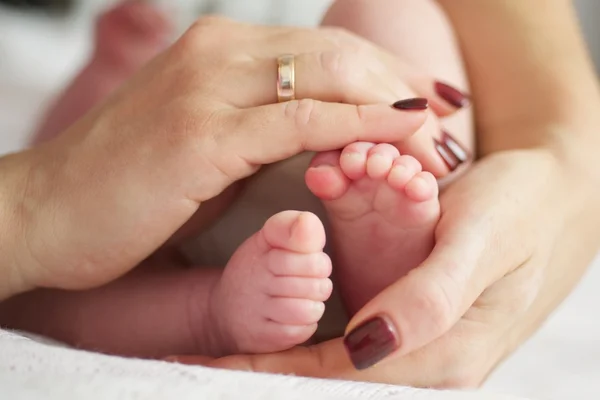 Matka drží nohy novorozenců — Stock fotografie