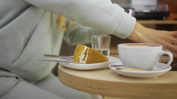 En kvinna äter en kaka på ett café och dricker hett bär te, har en bra tid, har en vila — Stockvideo