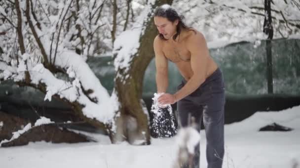 Taekwondo man, in de sneeuw in de winter, schopt, verhardt, veegt zichzelf met sneeuw, baadt in de sneeuw — Stockvideo