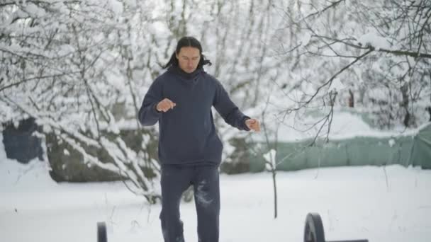 一个人在冬天的雪地里，火车在街上，变硬，热身 — 图库视频影像