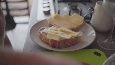 woman in the kitchen making a sandwich with bread, butter and cheese