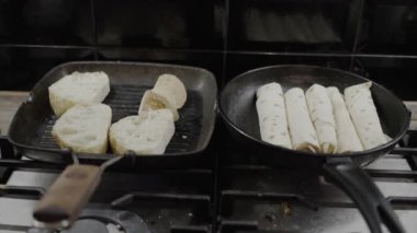 old frying pans, woman preparing a roll with cheese, dirty kitchen and hob