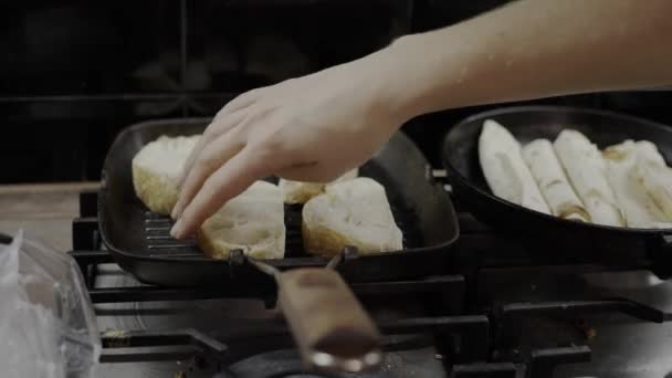 Old frying pans, woman preparing a roll with cheese, dirty kitchen and hob — Stockvideo
