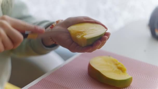 Flickan rengör, skär och äter mango — Stockvideo