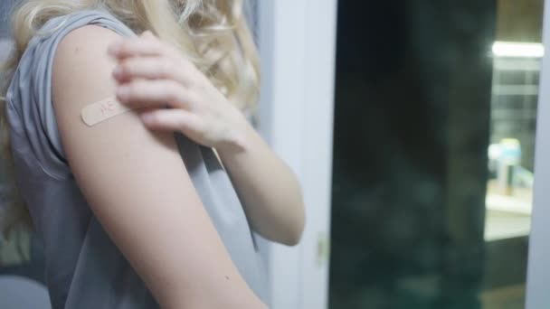 La fille se regarde dans le miroir, se regarde, un plâtre sur sa main — Video