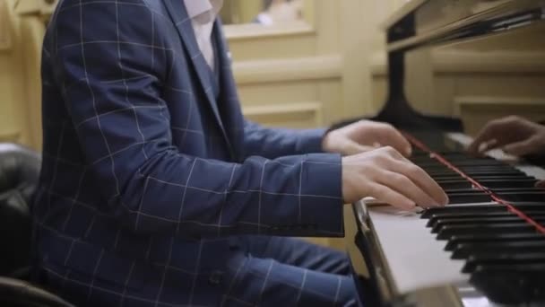 Un hombre con un hermoso traje toca el piano, de cerca — Vídeos de Stock