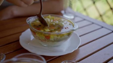 A woman has breakfast outdoors, in a summer vegetarian cafe, eats delicious vegan soup, slow motion, close-up,. High quality 4k footage
