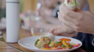 Bazı insanlar büyük bir masada yer, açık havada kahvaltı, salata, yakın plan sebze dürümleri. Yüksek kalite 4k görüntü