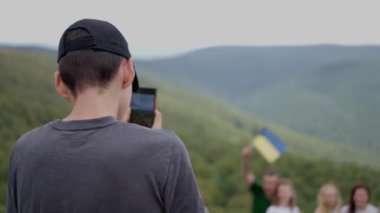 Köpekli turistler Ukrayna bayrağıyla bir dağın tepesinde fotoğraf çekiliyor. Ağır çekim. Sinyak. Ukrayna. 20.08.2022