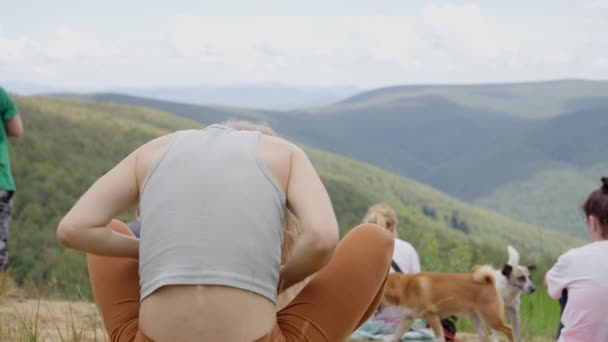 ウクライナのムカチェヴォだ 8月20日 2022年 旅行者は 長いブロンドの髪の女性が山の上に座って 草の上に座って 上昇した後 空を見上げます スローモーション — ストック動画