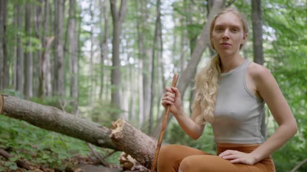 山の中の観光客 森の中の倒木に座っているブロンドの女性 スローモーション 高品質の4K映像 — ストック動画