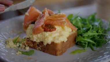 Kafedeki bir kadın çırpılmış yumurta, ekmek ve somon yer. Yakın çekim, yavaş çekim. Yüksek kalite 4k görüntü