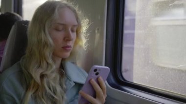 Yorgun, sarışın bir kadın, trende telefonda sohbet ediyor. Ağır çekim. Yüksek kalite 4k görüntü