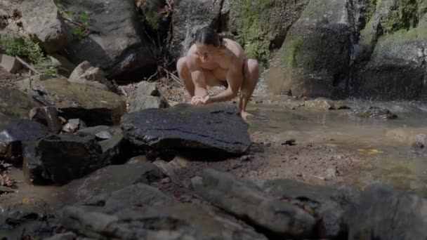 裸の胴を持つ男のアスリートは 水泳のトランクで 山の川で自分自身を洗います スローモーション 高品質4K映像 — ストック動画