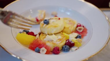 Peynirli kek, ahududu ve yaban mersinli şurup, yakın plan, çatallı el. Ağır çekim. Yüksek kalite 4k görüntü