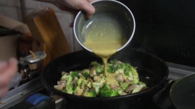 Bir kadın tavada mantarlı brokoli pişiriyor, ocakta yemek pişiriyor, yakın plan. Yüksek kalite 4k görüntü