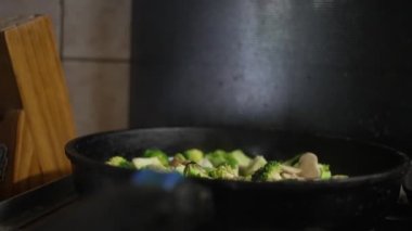 Bir kadın tavada mantarlı brokoli pişiriyor, ocakta yemek pişiriyor, yakın plan. Yüksek kalite 4k görüntü