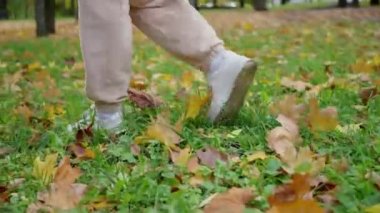 Siyah çizmeli kadınların ayaklarını kapat. Sarı sonbahar yeşilliklerinde yürü. Altın yapraklı, koyu renkli tek ayak yolu. Yüksek kalite 4k görüntü
