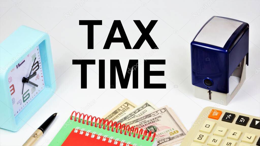 Tax time. An inscription on the background of banknotes, a calculator and hours of reminders about the planning of payment of bills.