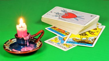 Tarot kartları ve bir mum. Antik semboller sistemi gizli okült bilgiyle ilişkilendirilir ve gizemli kabul edilir. Kehanet, geçmiş ve gelecek tahminleri için kullanılır..