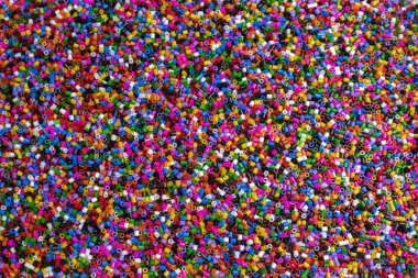 Small cylindrical pieces of plastic of multiple colors creating a colorful and fun texture special for backgrounds and graphic resources