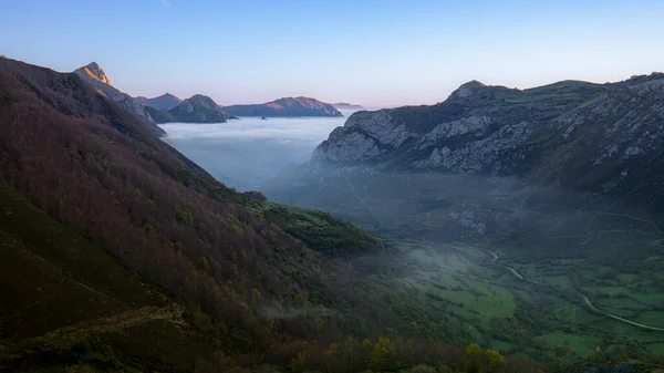 Landscape at dawn where we see the mountains and the valley of the Somiedo Natural Park in Asturias, Spain, with low clouds or mist in the green valley.