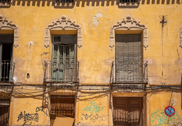 バルコニーと窓のある古い建物のファサードは非常に悪化し 落書きや黄色のファサードの亀裂 — ストック写真