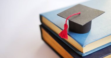 Kitap yığınında mezuniyet şapkası. Üniversite diploması konsepti 