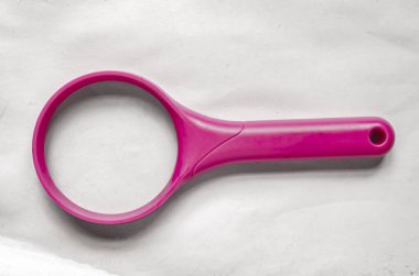 Pembe bir çerçeve büyüteç beyaz bir kağıdın üzerinde duruyor..