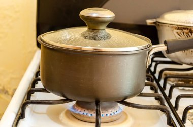 Soba ocağının alevi, içinde su damlacıkları olan cam bir kapakla kaplı siyah, yapışmaz bir tencerenin altında yükselir..