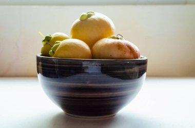 Bu, sarı olgun elmalarla dolu kahverengi şeritli bir tabağın yakın çekimi..