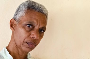 A senior woman with short trimmed black and white hair is looking sideways.