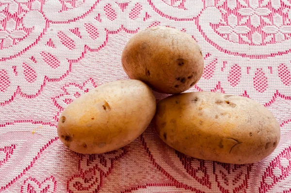 三个爱尔兰土豆坐在红白相间的花边桌布上 — 图库照片