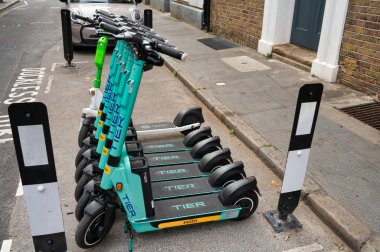Londra, UK- 3 Mayıs 2022: Kademe kiralama scooter 'ları Londra' da bir caddeye dizildi