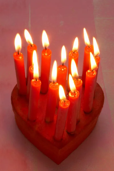 在礼品盒上以心形燃着红色的蜡烛 — 图库照片