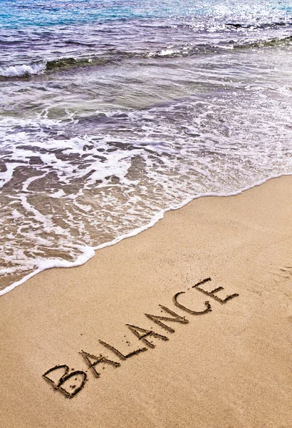 Word BALANCE written on sand, with sea waves in background — Stock Photo, Image