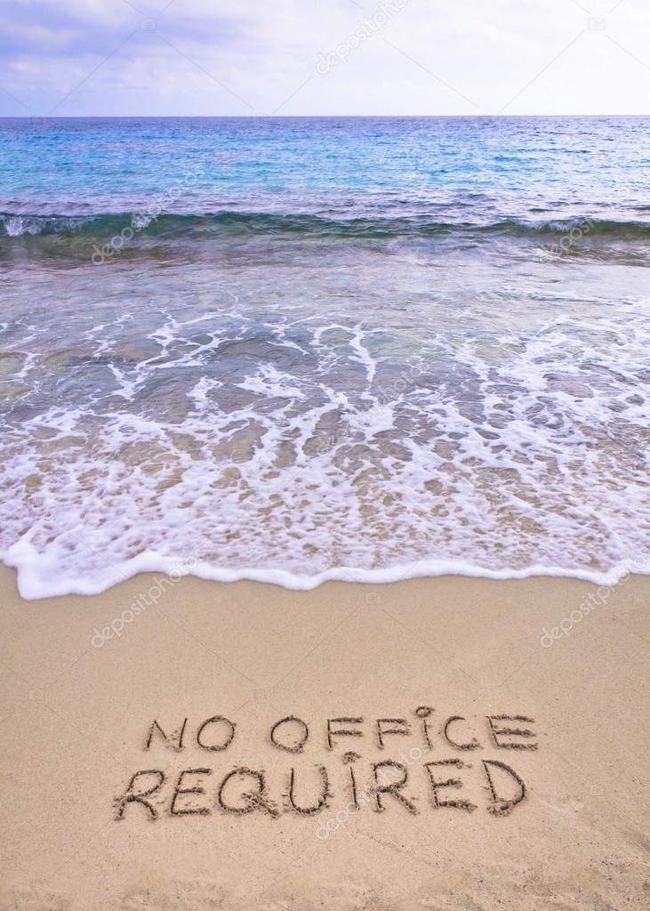 No office required written on sand, blue ocean water in background