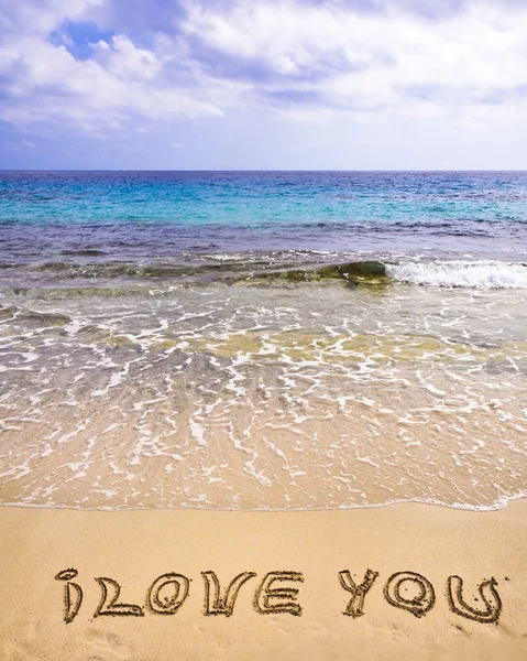Palabras que TE AMO escritas en la arena, con olas en el fondo — Foto de Stock