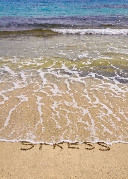 Slova stresu na písku, vypláchnuté vlny — Stock fotografie