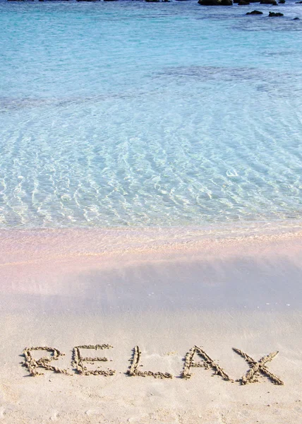 Koppla av ord skrivna i sanden, på en vacker strand med klarblå vågor i bakgrunden — Stockfoto
