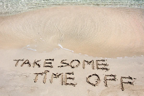 Take some time off written on sand on a beautiful beach, blue waves in background — стоковое фото