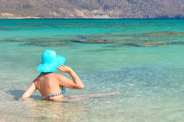 Schöne junge Frau im Badeanzug mit Sonnenhut, entspannt am sonnigen Strand — Stockfoto