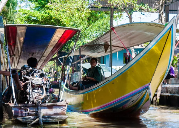 Thajská místní obyvatelé prodávají potraviny a suvenýry na slavné damnoen saduak plovoucí trh v Thajsku, v staré tradiční způsob prodeje od malých člunů. — Stock fotografie