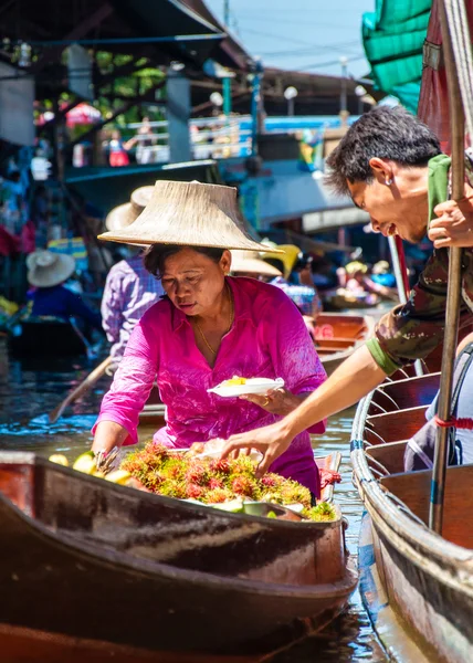 Thai locals sell food and souvenirs at famous Damnoen Saduak floating market in Thailand, in the old traditional way of selling from small boats. — Stock Photo, Image